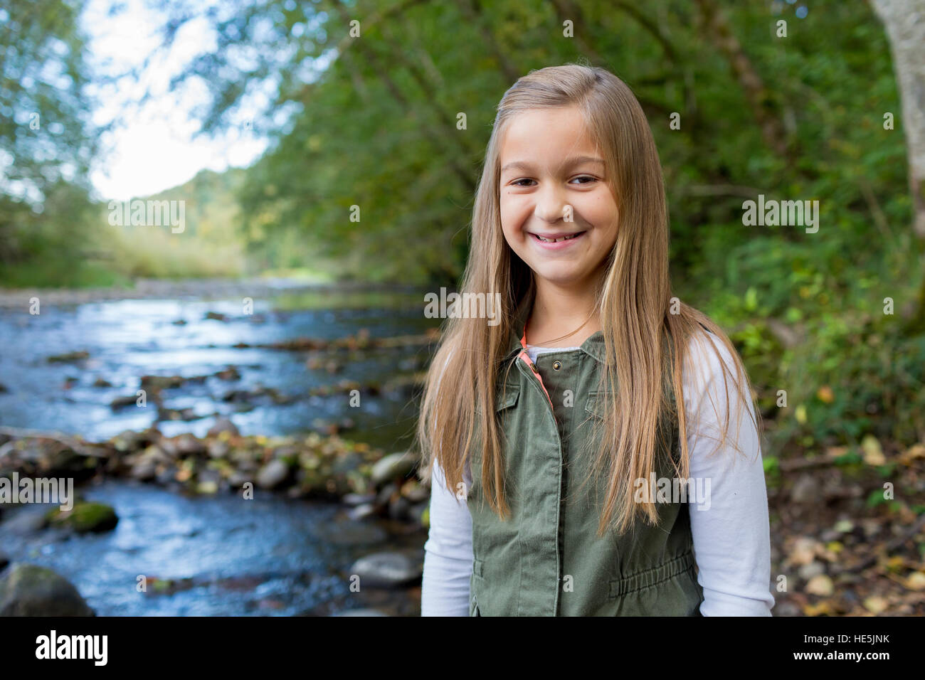 Jeune fille dans un gilet vert posant pour un portrait de vie en plein air le long des rives de la rivière McKenzie dans l'Oregon. Banque D'Images