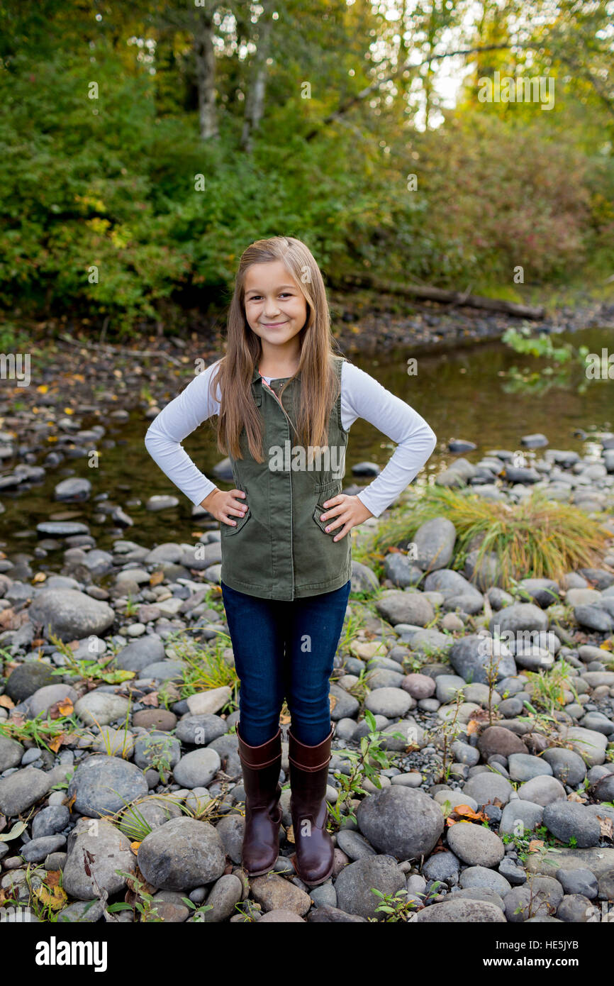 Jeune fille dans un gilet vert posant pour un portrait de vie en plein air le long des rives de la rivière McKenzie dans l'Oregon. Banque D'Images