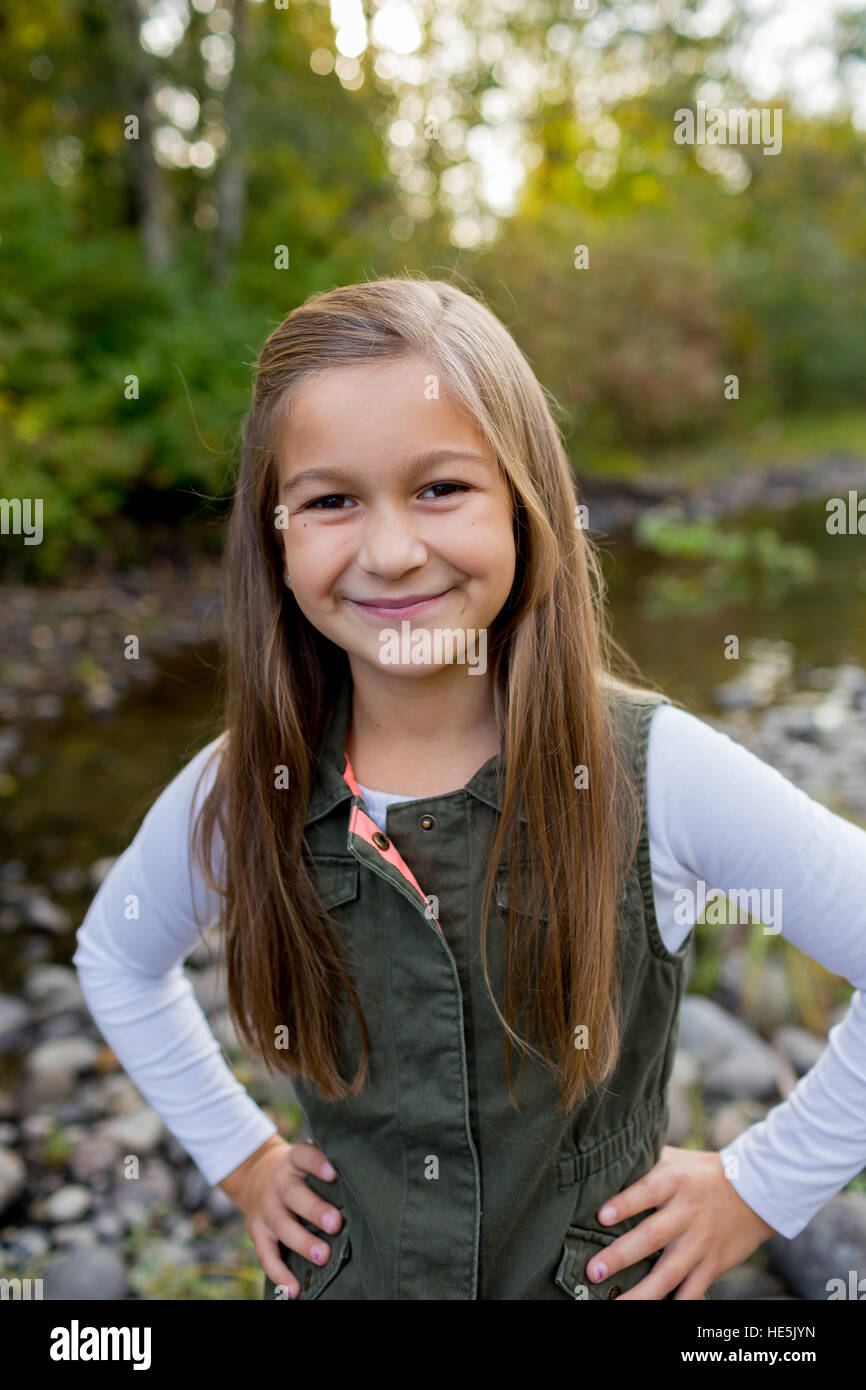 Jeune fille dans un gilet vert posant pour un portrait de vie en plein air le long des rives de la rivière McKenzie dans l'Oregon. Banque D'Images