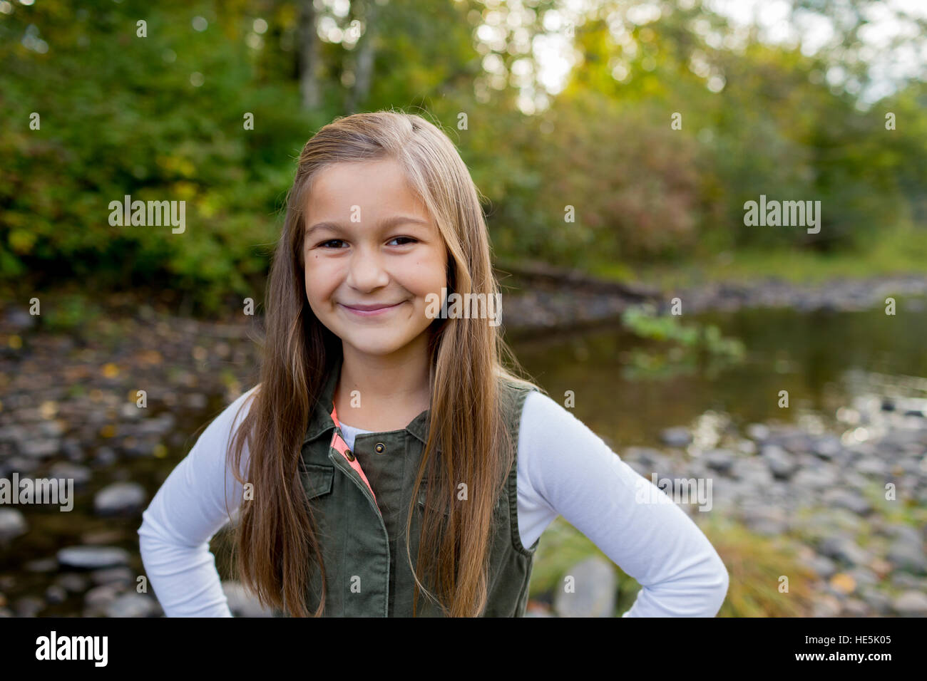 Jeune fille dans un gilet vert posant pour un portrait de vie en plein air le long des rives de la rivière McKenzie dans l'Oregon. Banque D'Images