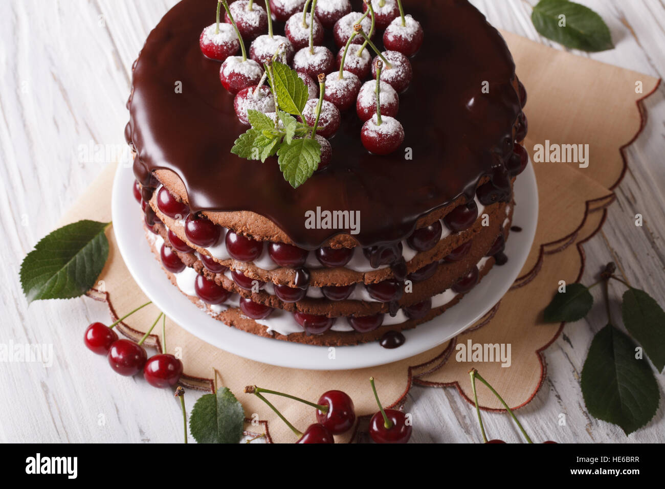 Grand gâteau avec glaçage au chocolat et cerises sur une plaque horizontale de près. Banque D'Images