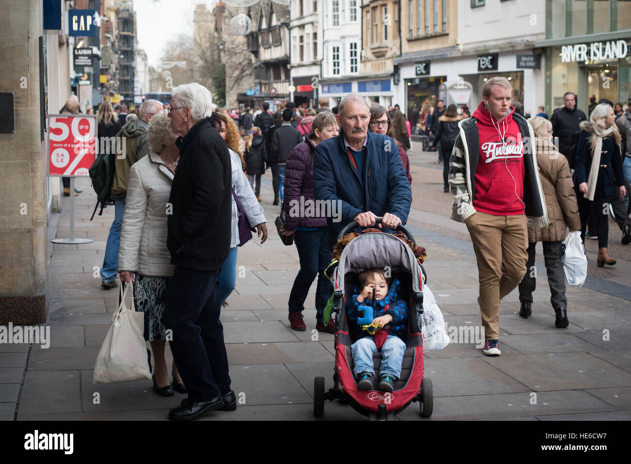Vieil homme poussant tout-petit dans rue commerçante animée d'Oxford, UK Banque D'Images