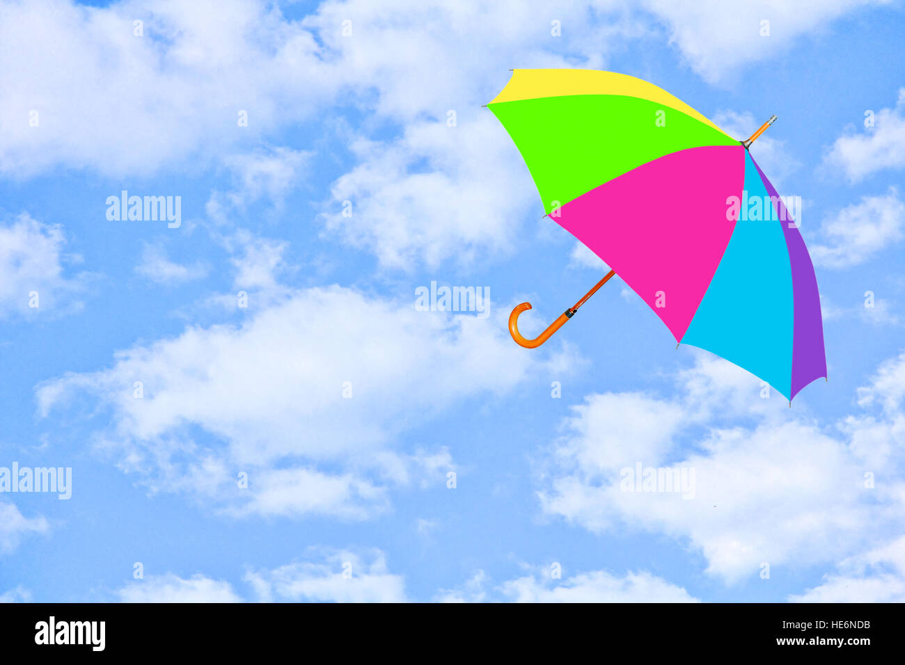 Parapluie multicolore vole dans le ciel contre des nuages d'un blanc pur.Mary Poppins Umbrella.vent de changement concept. Banque D'Images