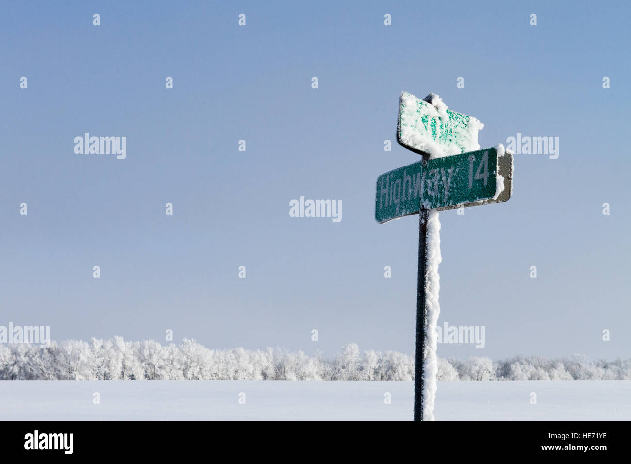 Highway street sign couvert de givre et de neige avec de la neige blanche couverte de champs et arbres en arrière-plan Banque D'Images