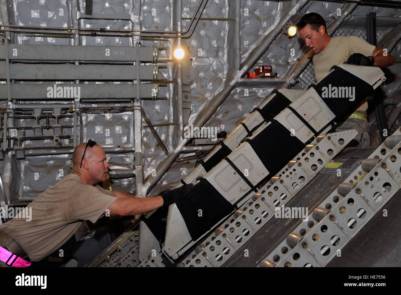 Le s.. Kevin MCINTYRE passe plié sièges passagers à Tech. Le Sgt. Jonathan Bronson ; tant aériens porteurs dans le 447e Escadron de préparation logistique expéditionnaire, 10 août 2010, à la base aérienne de Sather, de l'Iraq. Les Aviateurs déchargé 12 palettes de fret, puis reconfigurée à l'avion de transport de passagers en moins d'une heure. Le C-17 est à l'appui du personnel du redéploiement des forces américaines responsables effectifs de forces armées de 50 000 hommes d'ici la fin du mois d'août lors de l'Opération Liberté pour l'Irak se termine, et l'opération aube nouvelle commence. ( Hauts Airman Perry Aston) (publié) Banque D'Images