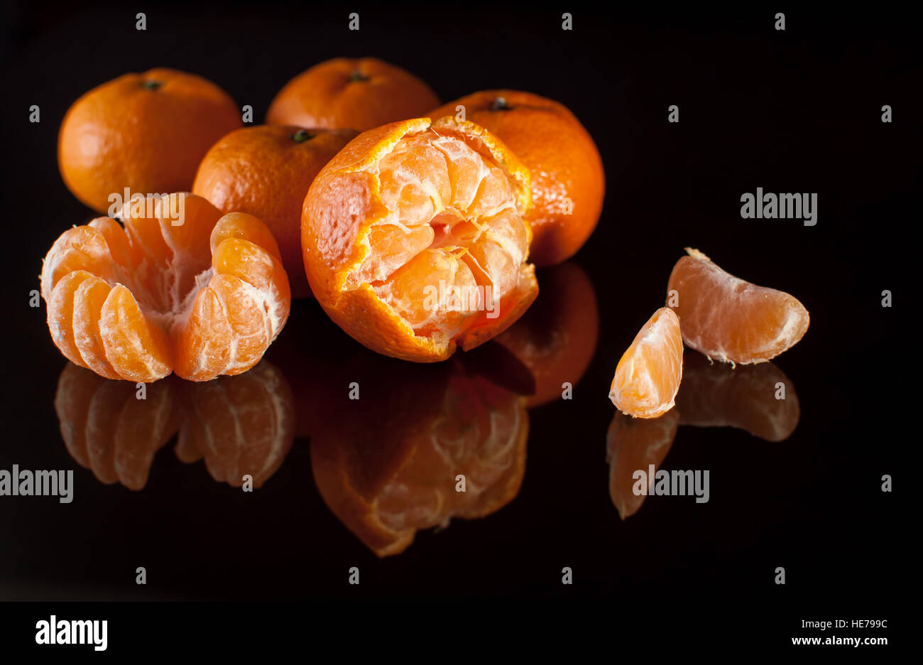 Groupe de mandarins avec miroir réflexion sur fond noir de près. Studio light. Banque D'Images