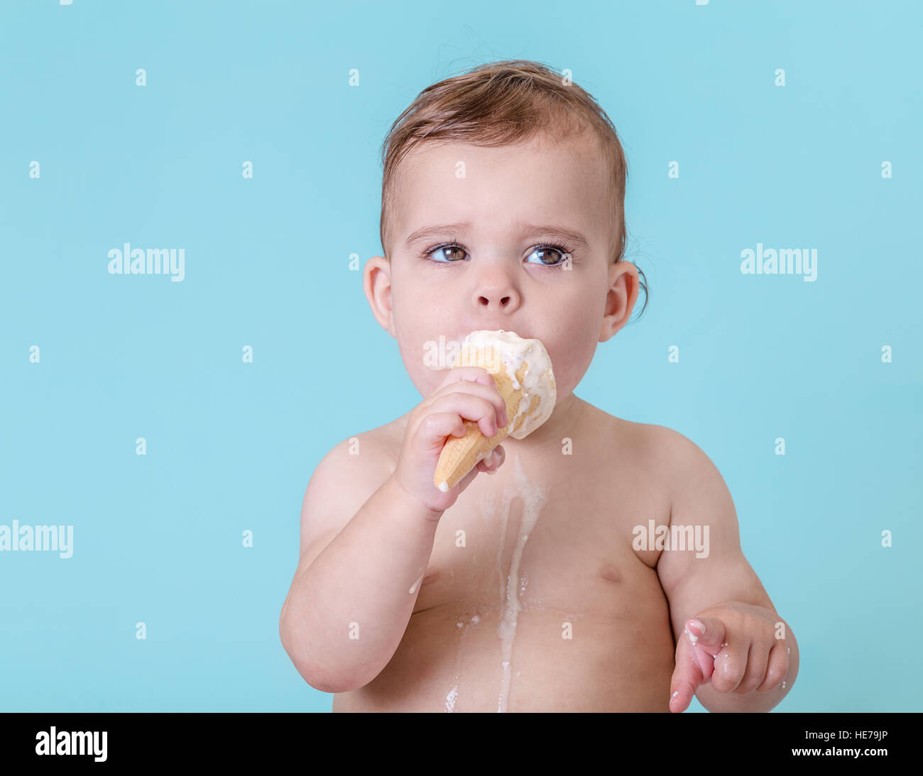 Joli bébé fille avec de la crème glacée fondue sur fond bleu clair Banque D'Images
