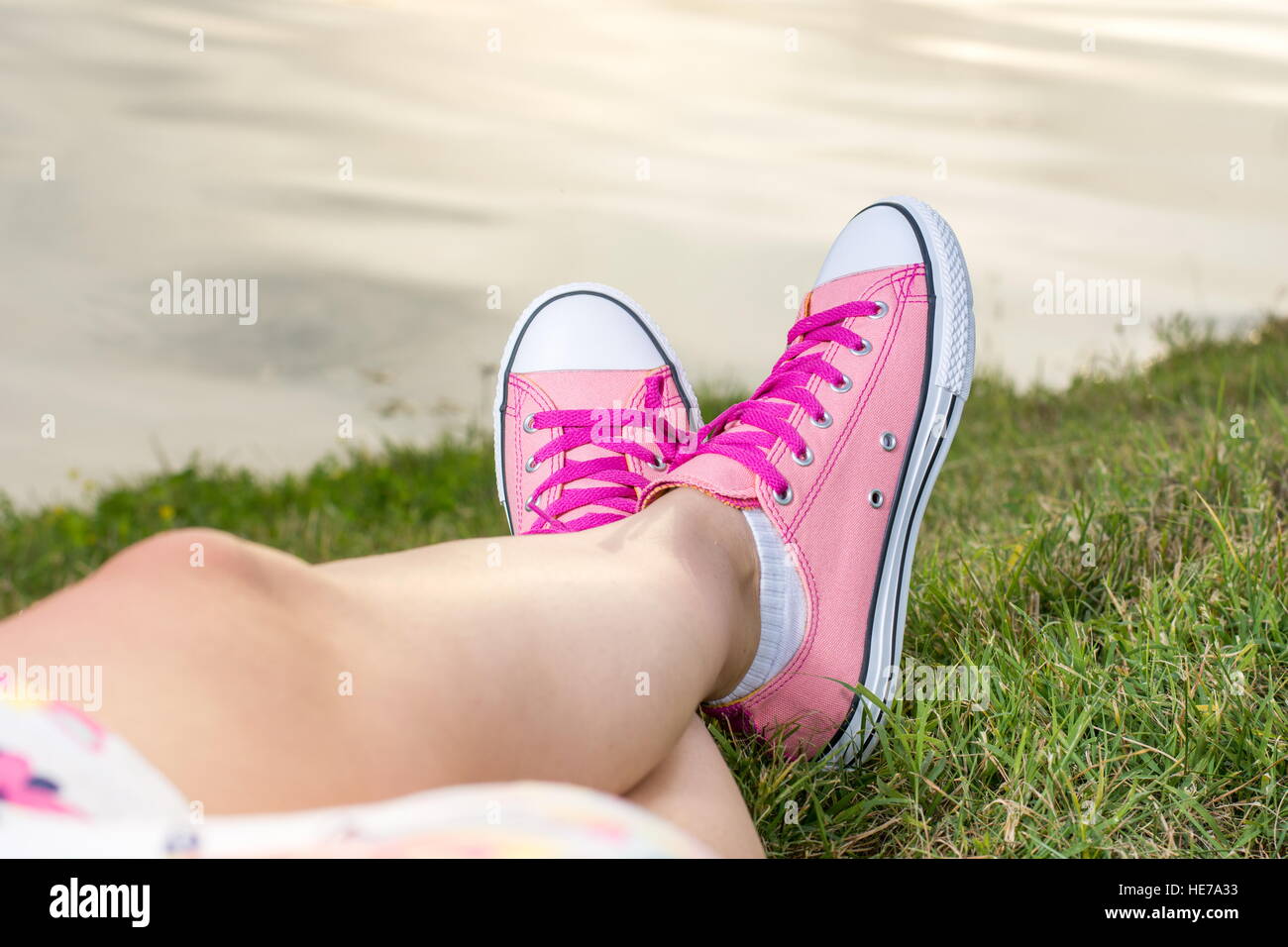 Profitant par le lac. Femme jambes portant des chaussures rose Banque D'Images
