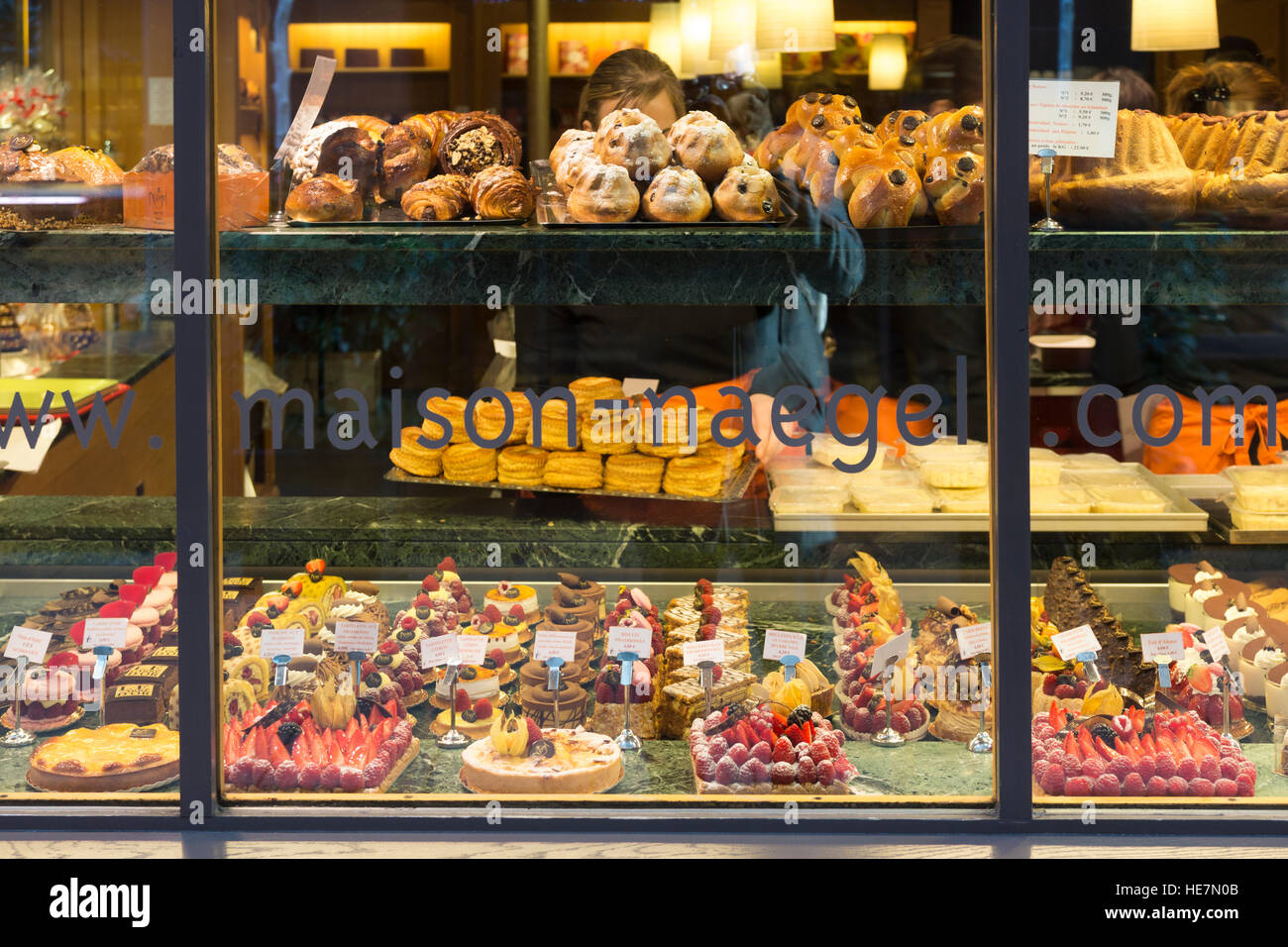 Une vitrine illuminée avec une délicieuse pâtisserie française, y compris des gâteaux, des biscuits et d'autres desserts à la Maison-Naegel, Strasbourg, France Banque D'Images