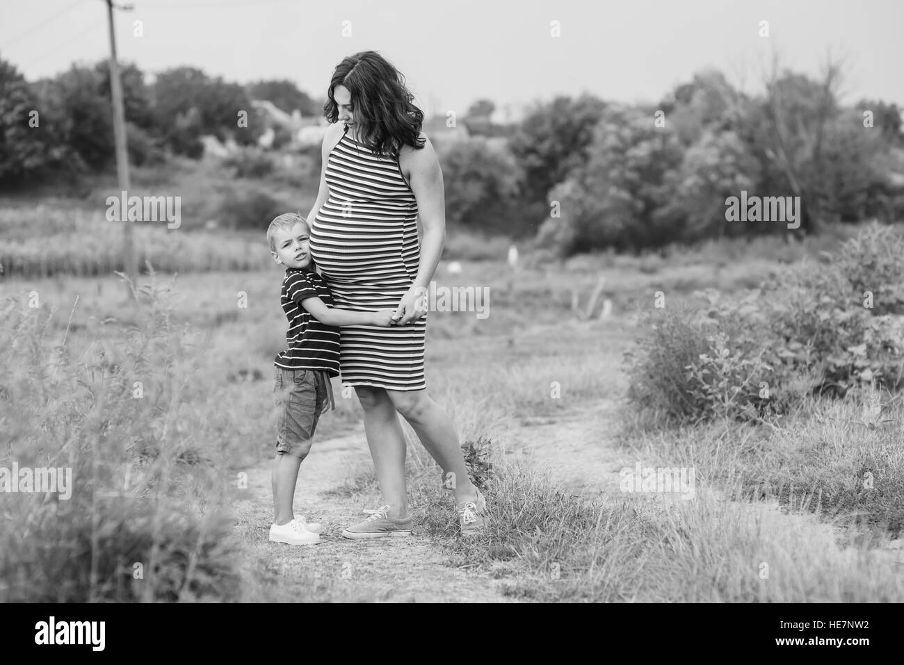 Femme enceinte à la campagne avec son fils. Serrant ses enfants mère enceinte. Photo en noir et blanc Banque D'Images