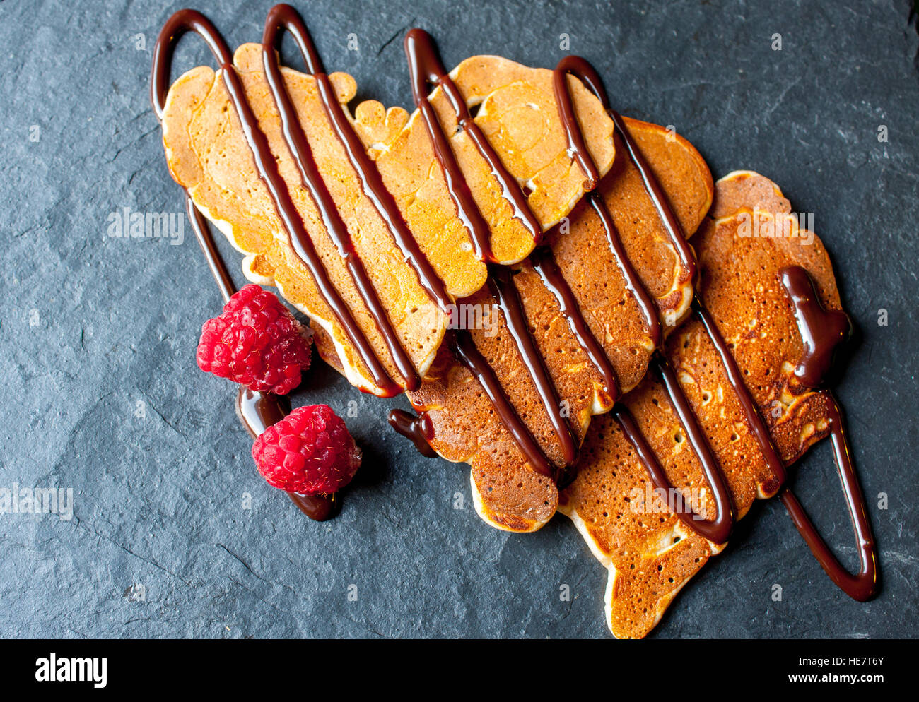 Des crêpes en forme de coeur avec le sirop de chocolat et de framboises sur la Saint-Valentin. Banque D'Images