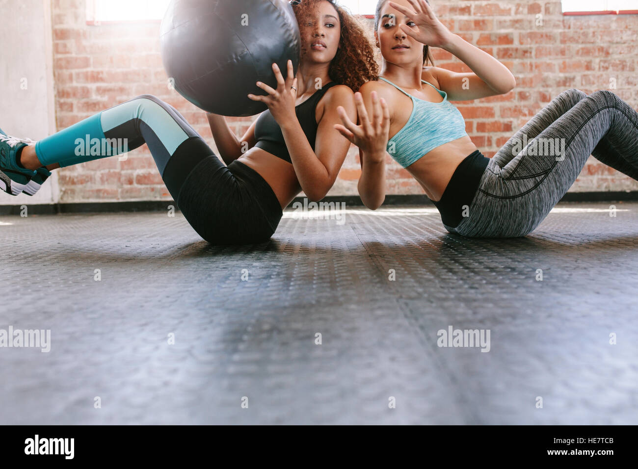 Deux jeunes femmes s'entraîner avec le ballon d'une salle de sport. Les filles qui travaillent dans une salle de sport. Banque D'Images