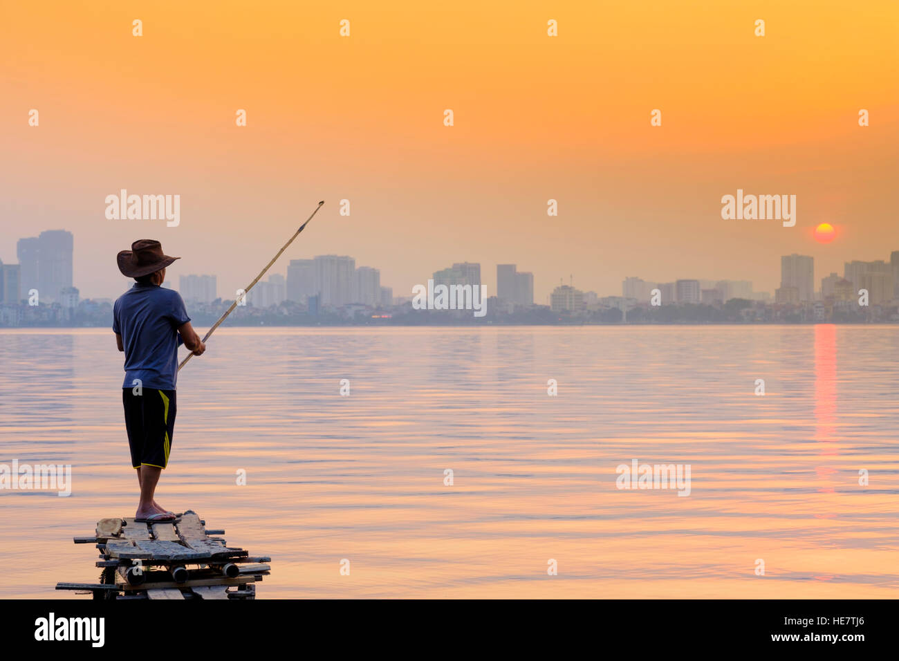 Un homme la pêche sur le lac de l'ouest de Hanoi, Vietnam Banque D'Images