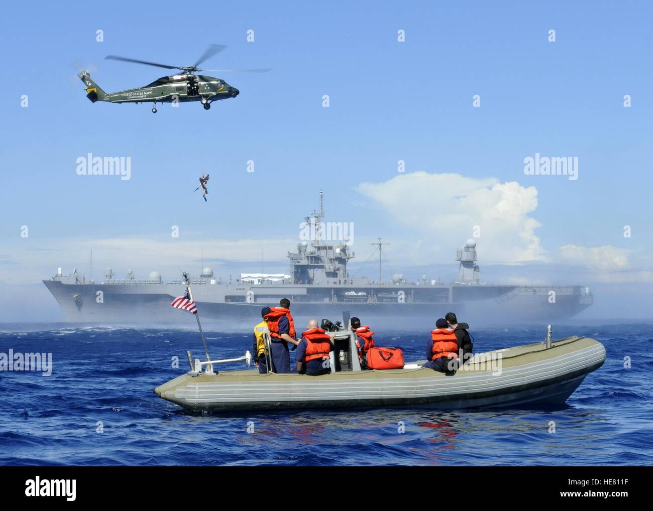 Les marins américains sur un radeau pneumatique regarder un pont aérien d'hélicoptères de recherche et de sauvetage d'un nageur de l'océan lors d'un exercice d'entraînement à côté de l'USN Blue Ridge-class USS Blue Ridge le 18 février 2009 dans l'océan Pacifique. Banque D'Images