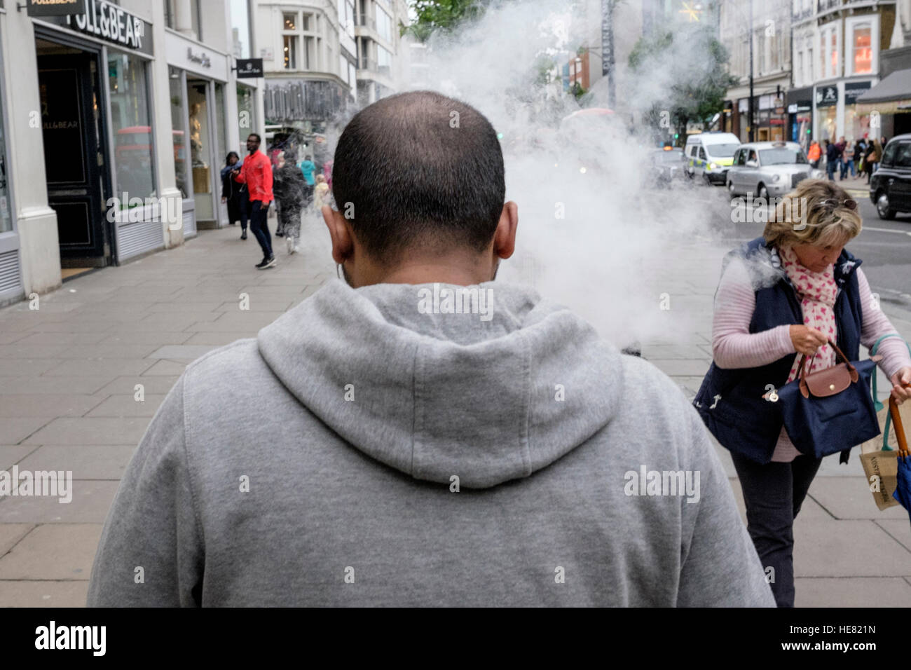 L'homme exhale e-fumée de cigarette à l'origine passer par à prendre des mesures d'évitement. Banque D'Images