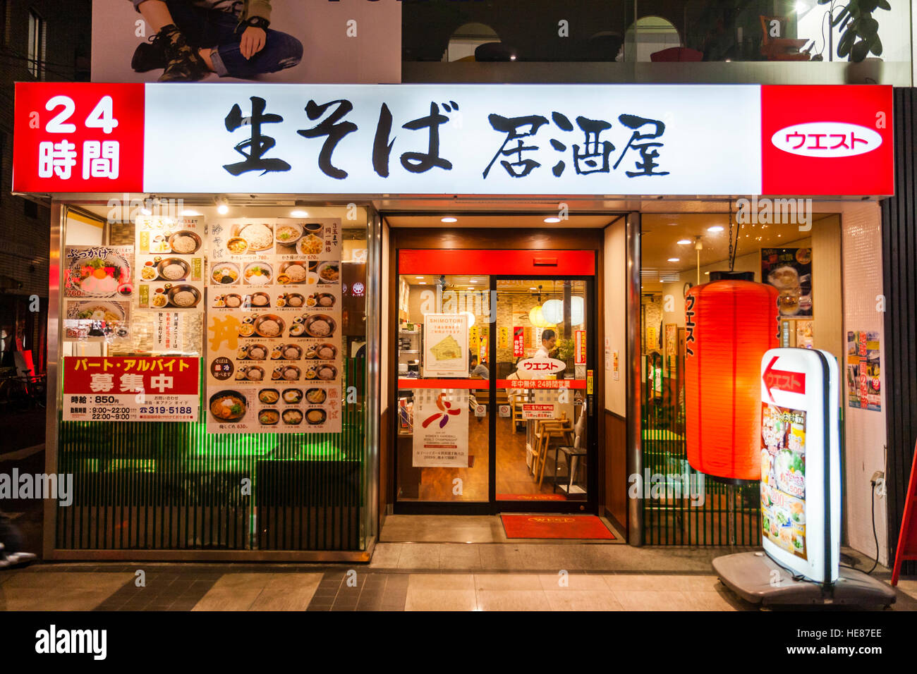 Le Japon, Kumamoto, Shimotori Arcade Street. Nouilles soba sarrasin restaurant, entrée privée. La façade de verre, avec des enseignes lumineuses de sélection ci-dessus. La nuit. Banque D'Images