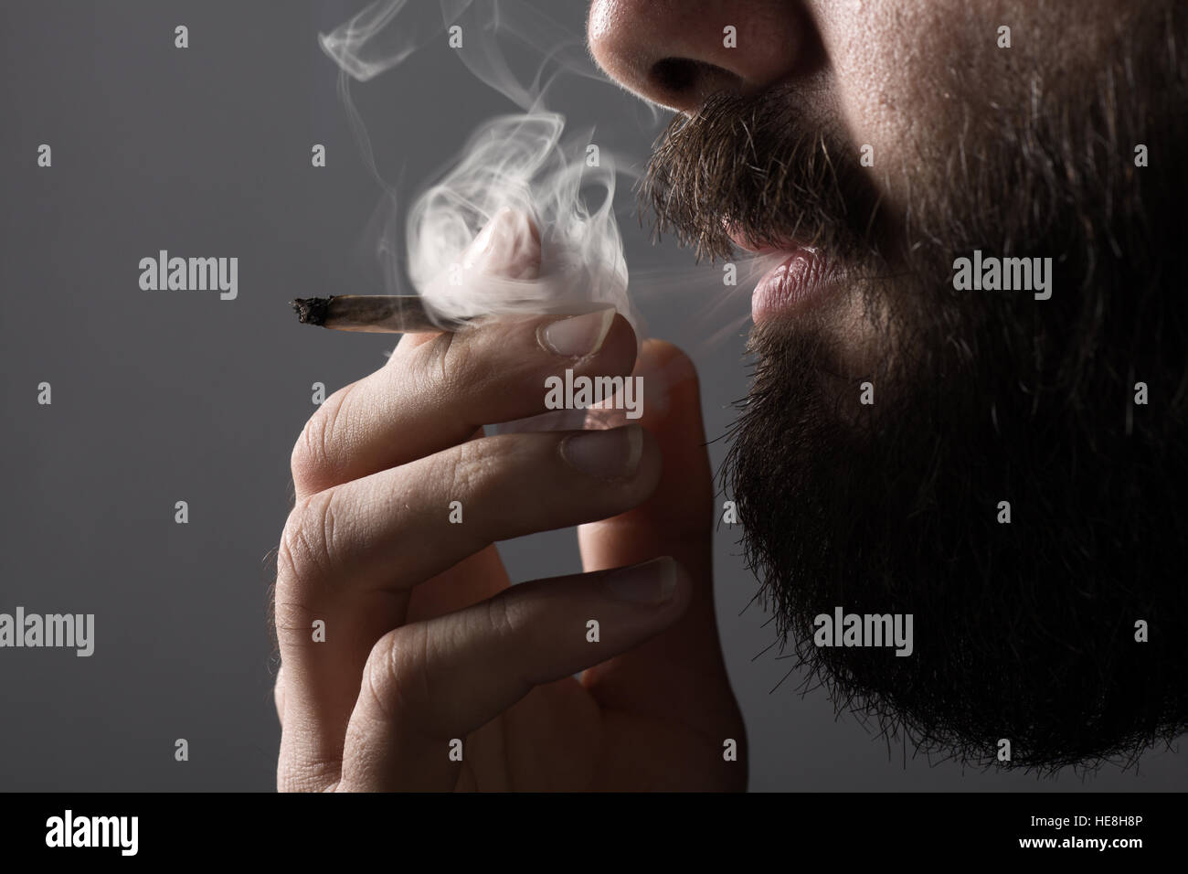Détail d'un homme avec une barbe de fumer une cigarette Banque D'Images