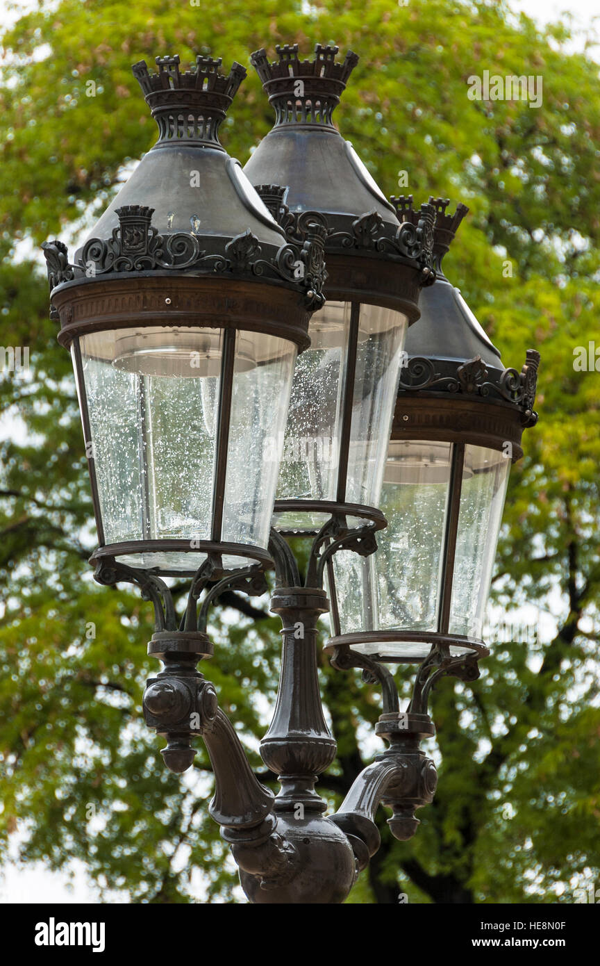 Lampadaire en métal à l'ancienne avec trois lumières avec en arrière plan  l'arbre vert à Paris, France Photo Stock - Alamy