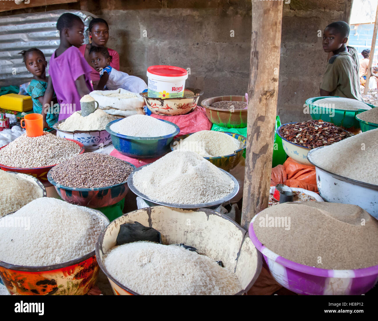 Des enfants sont assis parmi des bols empilés de riz et de haricots à un étal de marché à Kabala, en Sierra Leone. Banque D'Images