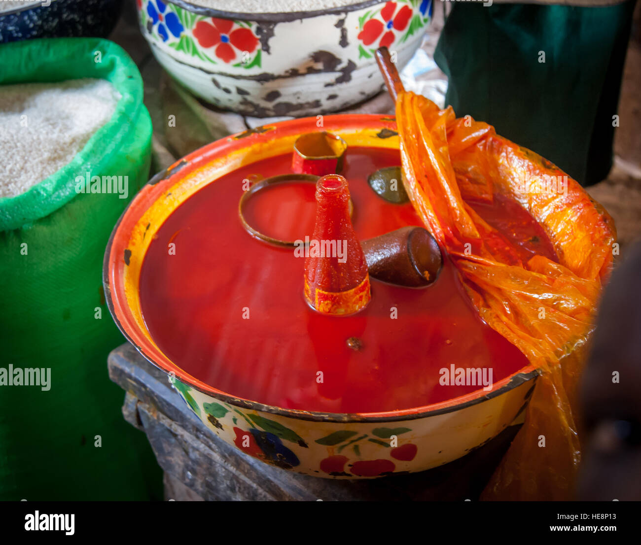 Huile de palme rouge avec bouteille graduée et tasse dans un bol sur le marché à Makeni, Sierra Leone. De grandes quantités d'huile de palme sont consommées en Afrique de l'Ouest. Ici, il est utilisé frais et non traité. En raison de la teneur élevée en bêta-carotène, il est de couleur rouge Banque D'Images