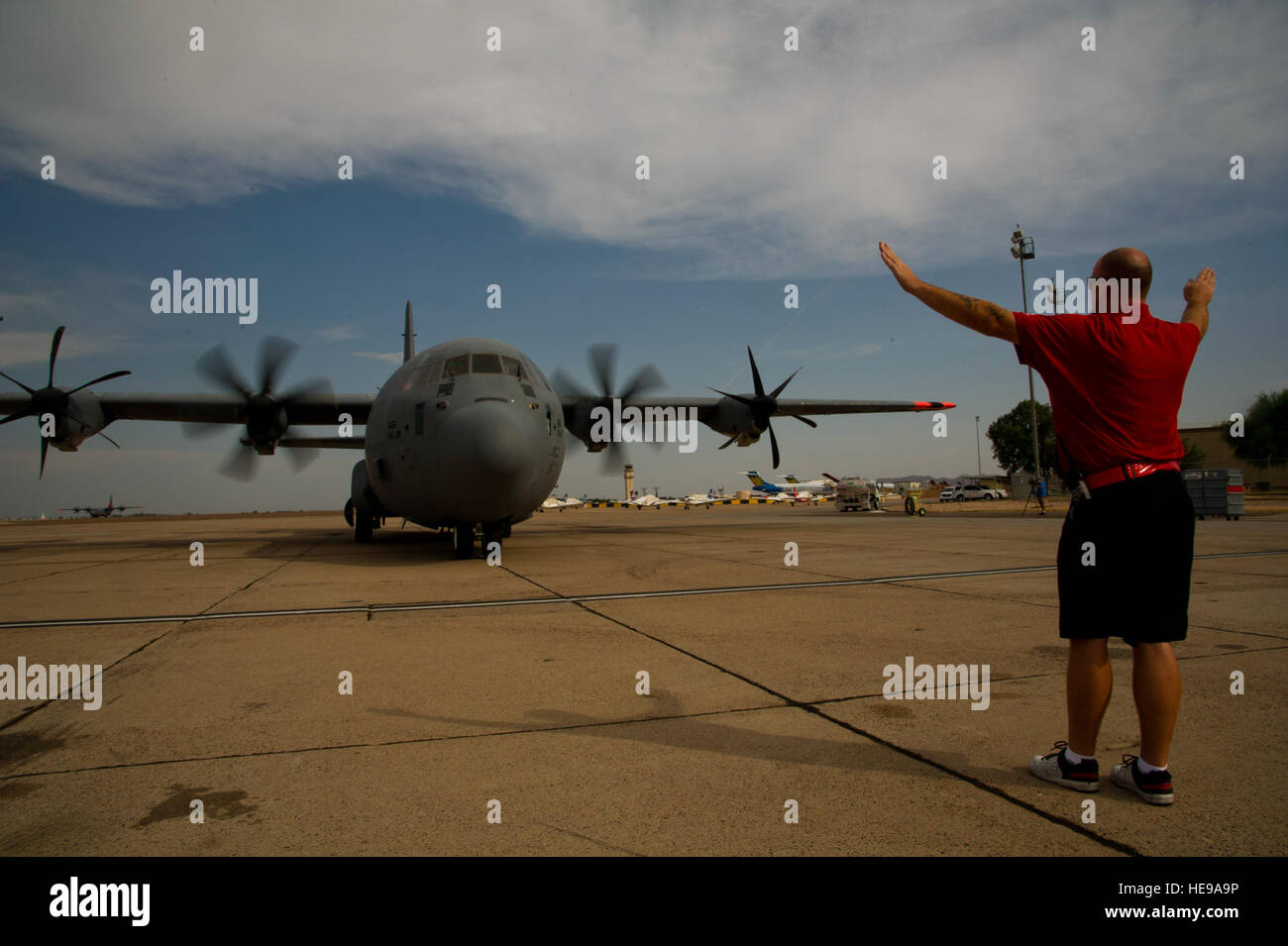 Un membre d'équipage au sol dirige un C-130 militaire du California Air National Guard's 146e Airlift Wing pour une place de stationnement dans le secteur Phoenix-Mesa Gateway Airport ici le 3 juillet 2013. L'avion et trois autres du même genre, toutes équipées avec le système de lutte contre les incendies en vol modulaire utilisé dans la lutte contre les feux de forêt lorsqu'il est installé dans la soute d'un C-130 ont été commandés, déplacé de la base aérienne Peterson, au Colorado, où ils avaient été la lutte contre les incendies depuis le 11 juin, à Mesa par les planificateurs à la Boise, Idaho, National Interagency Fire Center. MAFFS est un système de lutte contre l'incendie aérienne appartenant à t Banque D'Images