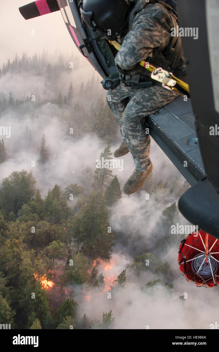 Le Sgt. Chris Boni, chef d'équipage de la Garde nationale de Californie, 1-140ème bataillon de l'Aviation (Air Assault) sur la base de formation conjointe de Los Alamitos (JFTB), les rejets de l'eau sur la tête arrosant le rim fire ci-dessous près de Yosemite National Park. La Rim Fire est maintenant la 14e plus grande forêt à l'histoire de la Californie. L'UH-60 Black Hawk équipages se battent contre la jante de forêt à l'appui de Bureau du Service des forêts des États-Unis et Cal feu.(U.S. Le sergent-chef de la Californie. Julie Avey/ libéré) Banque D'Images