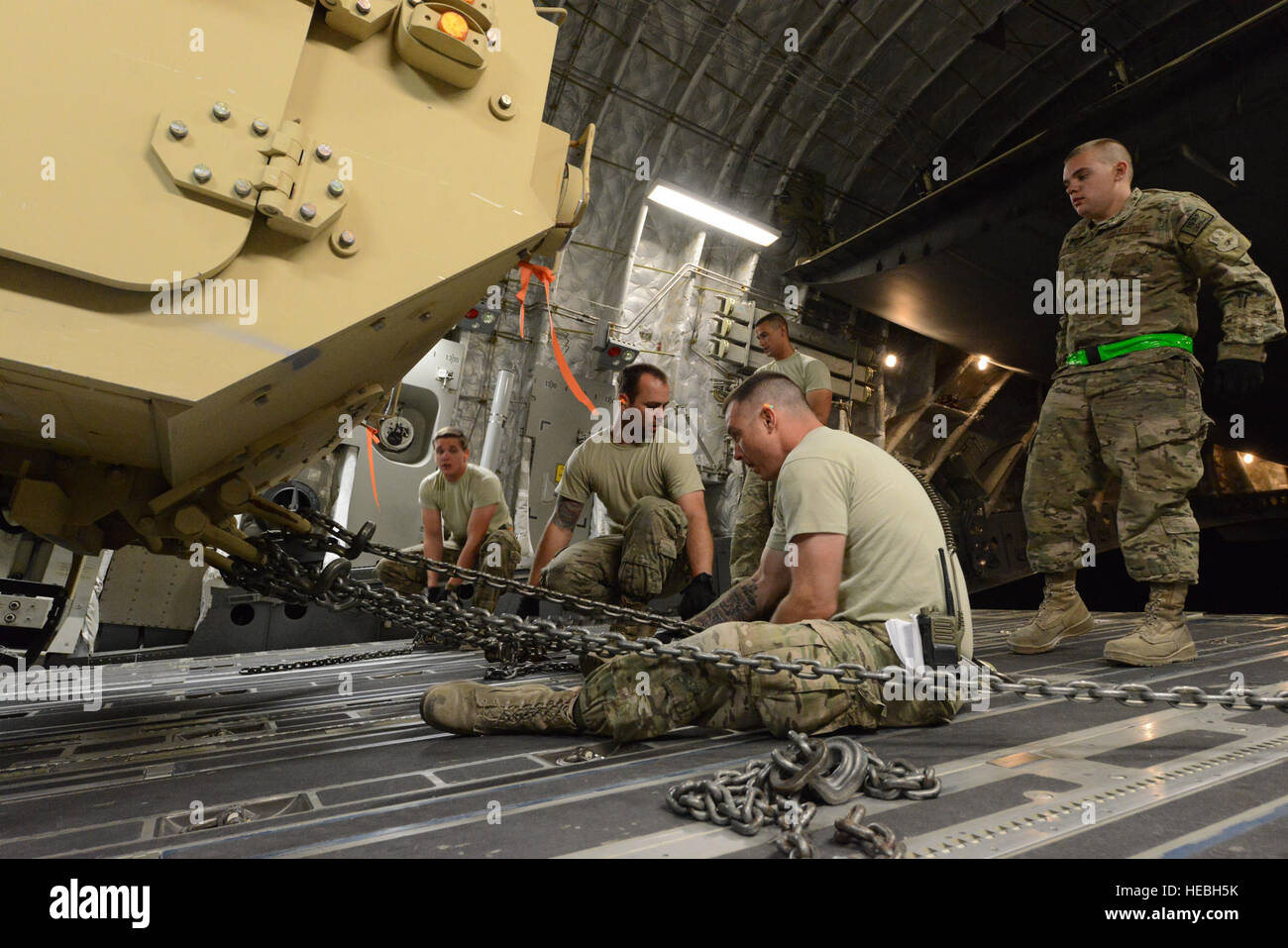 Aviateurs, affecté à la 455 e Escadron expéditionnaire port aérien travaillent ensemble à renforcer la sécurisation d'un des câbles de Mobilité élargi camion tactique à bord d'un C-17 Globemaster III après le déchargement six ambulances de l'air afghane à Bagram, en Afghanistan, le 20 juillet 2014. (U.S. Air Force photo par le Sgt. Cohen A. Young/libérés) Banque D'Images