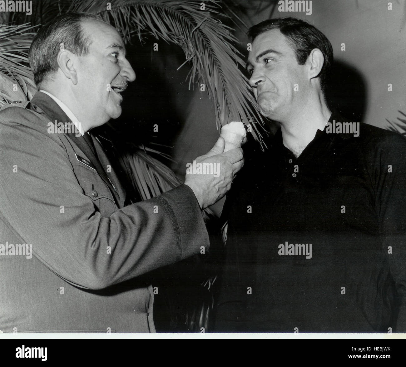 Sean Connery feint d'enfoncer un cornet de crème glacée à la vanille dans le Lieutenant-colonel à la retraite Charles Russhon's face au cours de la production de "Thunderball.' Russhon était le conseiller militaire du films de James Bond dans les années 60 et 70. Russhon et Connery devenus amis sur le plateau. Le Vanilla Ice cream cone avait une signification spéciale pour Russhon, qui a inspiré le personnage de Charlie 'Vanilla', une glace aimer mister fix-it, en ami et estimé du caricaturiste américain Milton Caniff bande dessinée 'Steve Canyon.' (Photo gracieuseté de Christian Russhon) Banque D'Images