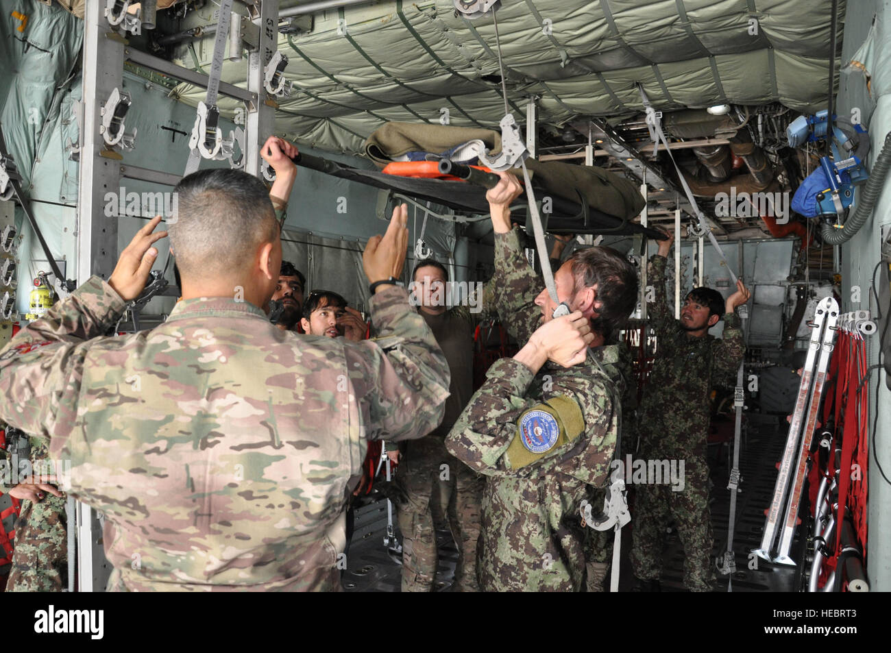 Former, conseiller, aider - Commande Air (TAAC-Air) conseillers fournissent des instructions à l'Armée nationale afghane des infirmiers de vol lors de la reconfiguration de la soute d'un C-130H Hercules du coin à filet metal épontilles qui détiennent des brancards pour une "simulation d'évacuation médicale", ou d'évacuation sanitaire, de vol à l'Aéroport International d'Hamid Karzaï, le 9 juillet 2015. TAAC-conseillers fournissent de l'air à l'entraînement hebdomadaire et ANA Afghan Air Force pour développer et accroître leurs capacités de combat medics. (U.S. Air Force photo/Capt. Eydie Sakura/libérés) Banque D'Images