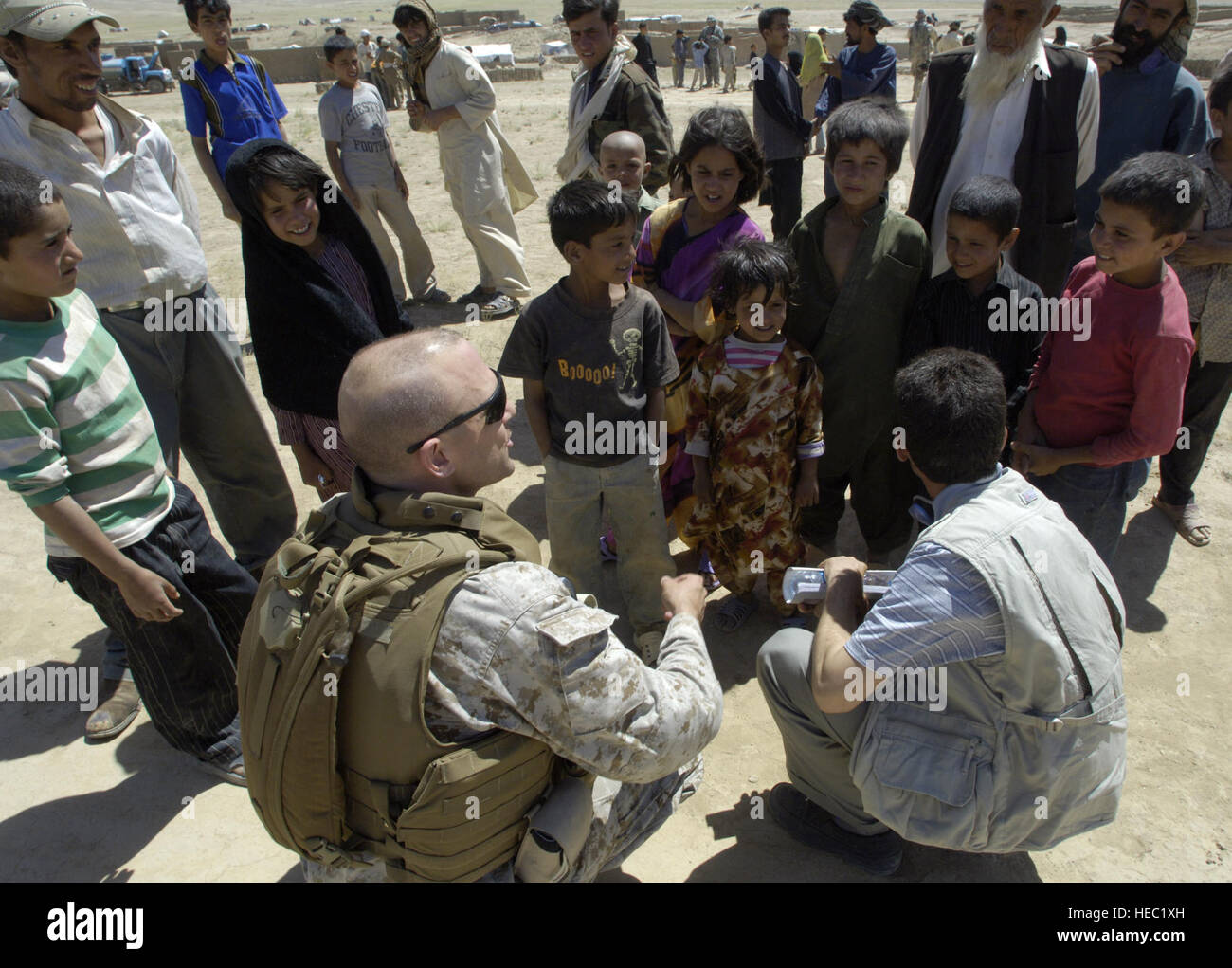 Le major du Corps des Marines américain Brian Rush(en bas à gauche), un membre de la transition conjointe de la sécurité (CSTC-A) des entretiens avec un groupe d'enfants après l'acheminement d'une des personnes déplacées internes (IDP) camp en dehors de Kaboul, Afghanistan, le vendredi 27 juillet 2007, d'offrir des dons envoyés depuis les Etats-Unis. Le camp abrite environ 585 familles. La CSTC-A, composé de membres et conjoints de militaires internationales, fonctionnaires et entrepreneurs basés à Camp Eggers, recueillir toutes les deux semaines en vertu de la communauté de bénévoles Relations (Magnétoscope) programme à réaliser les vêtements, jouets, Banque D'Images