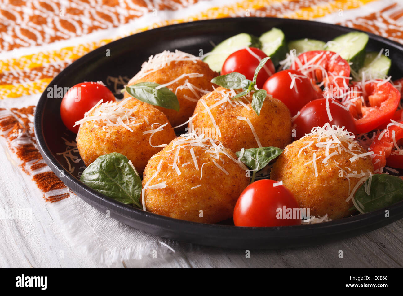 Boules de riz arancini frits et salade de légumes frais sur une plaque horizontale. Banque D'Images