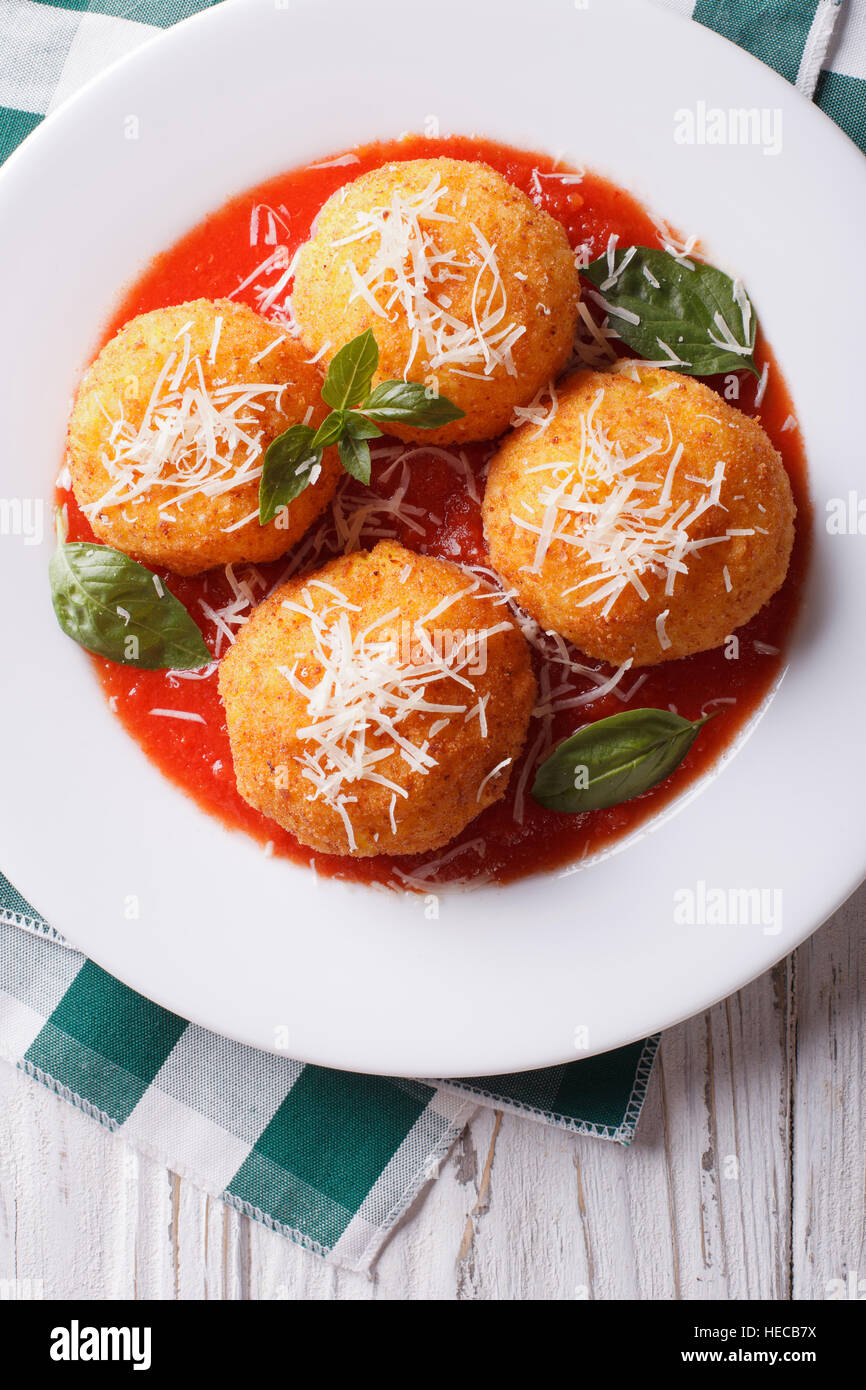 Arancini frits boulettes de riz avec de la sauce tomate fermer vers le haut sur la table. vertical vue d'en haut Banque D'Images