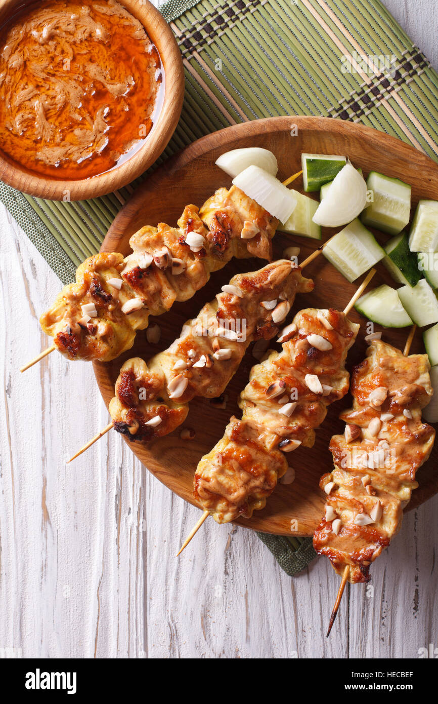 Satay de poulet avec sauce aux arachides et une délicieuse salade fraîche sur le gros plan de la plaque verticale Vue de dessus. Banque D'Images