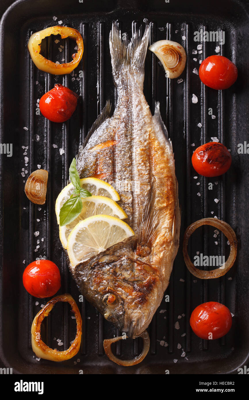 Poisson grillé dorado au citron et de légumes sur le grill. vertical Vue de dessus Banque D'Images