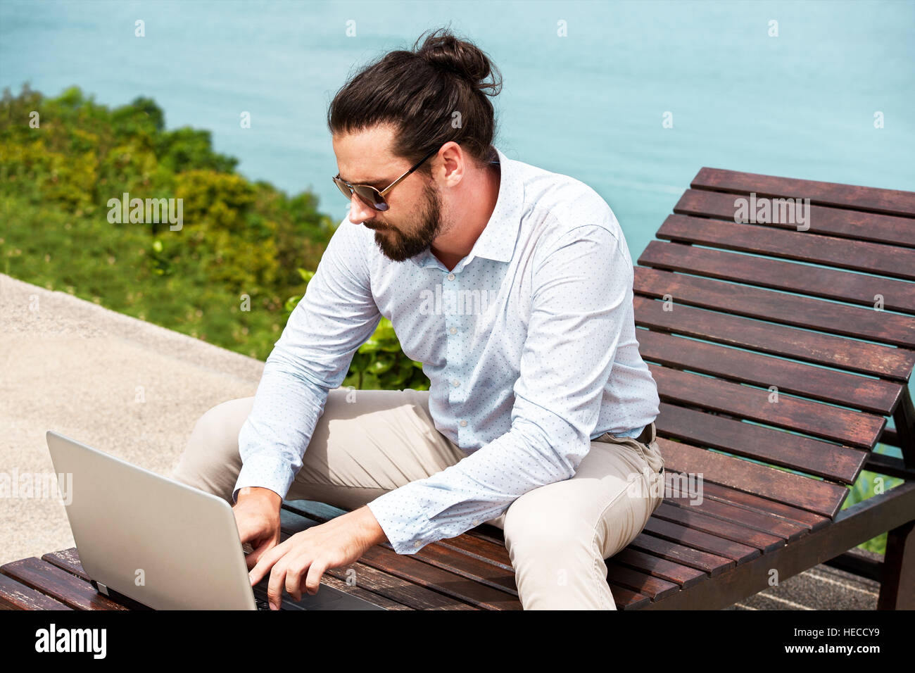 Businessman wearing a suit sur une chaise de la saisie de l'ordinateur portable sur la plage Banque D'Images