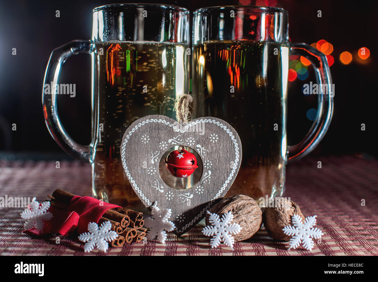 La veille du Nouvel An. Image drôle de deux verres de champagne, déco coeur, flocons, la cannelle et les noix sur le contexte des lumières bokeh. Banque D'Images