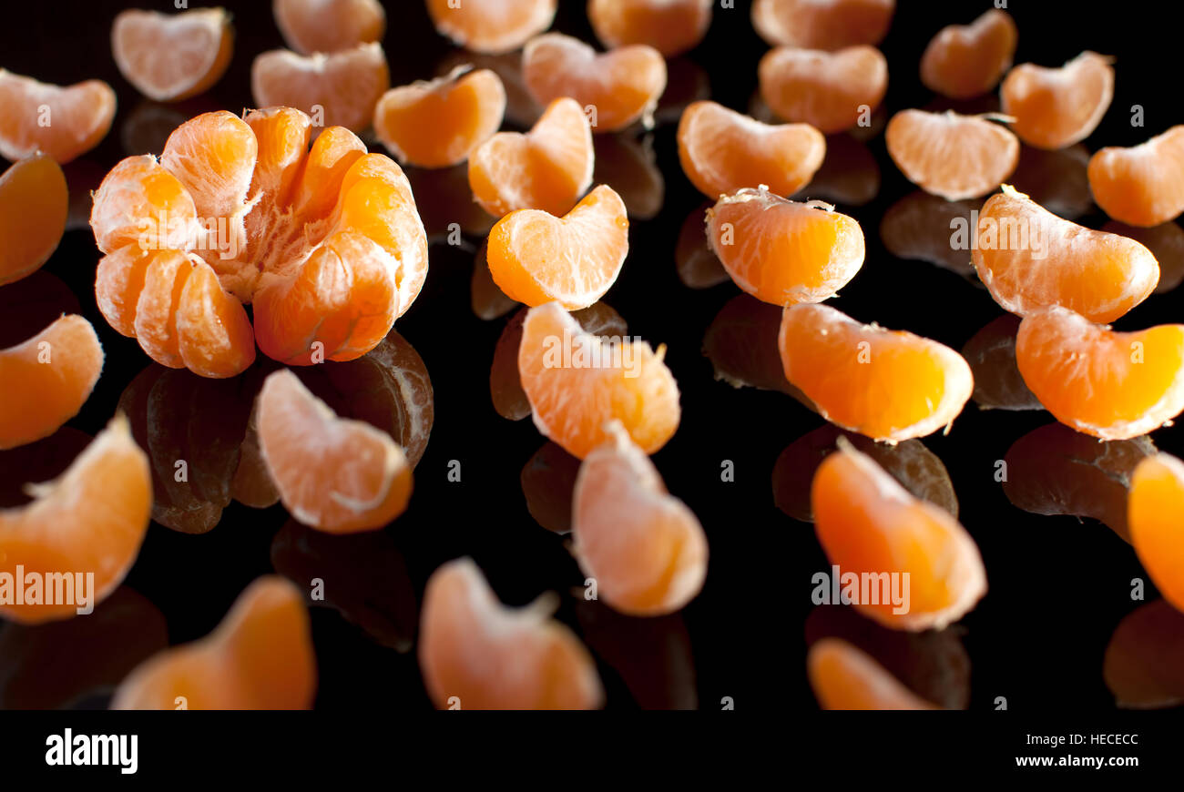 Groupe des tranches de mandarine avec miroir réflexion sur fond noir de près. Studio light. Banque D'Images