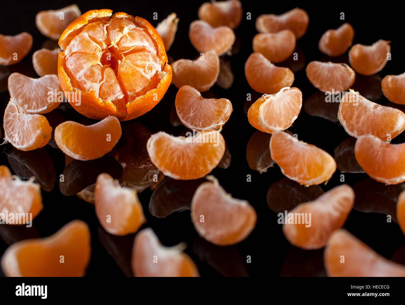 Groupe des tranches de mandarine avec miroir réflexion sur fond noir de près. Studio light. Banque D'Images