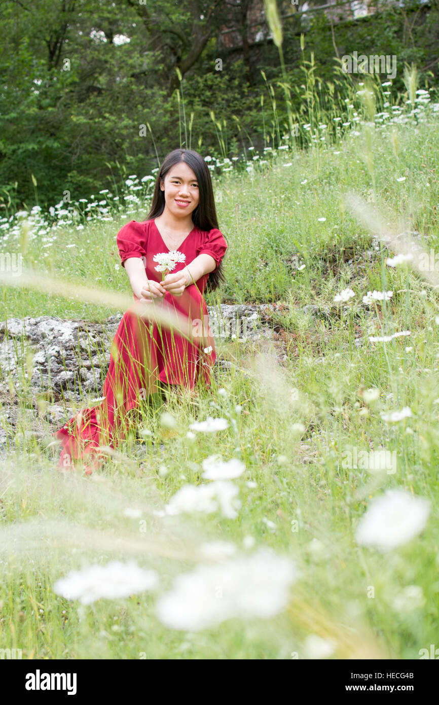 Femme Ypung en champ de fleur wearing red dress Banque D'Images