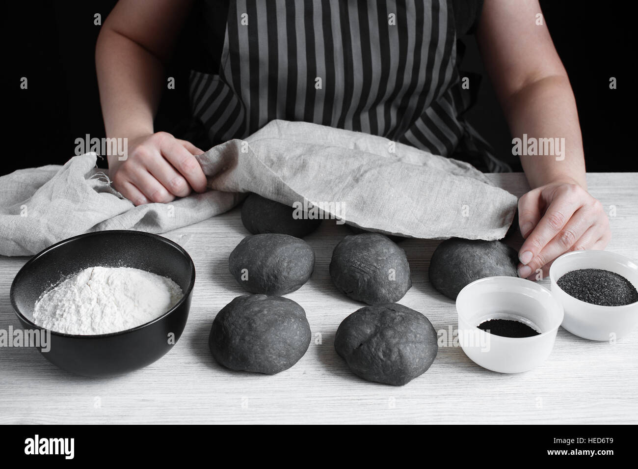 Les mains couvertes de sexe féminin les matières premières brioches avec une serviette de lin noir Banque D'Images