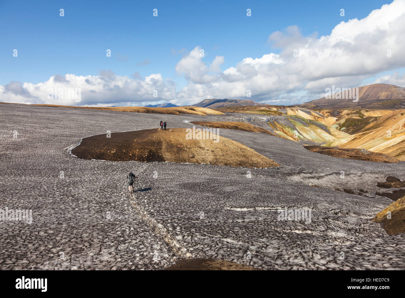 Les randonneurs traversant les champs de neige noirci de cendres volcaniques sur le sentier de randonnée Laugavegur Islande Banque D'Images
