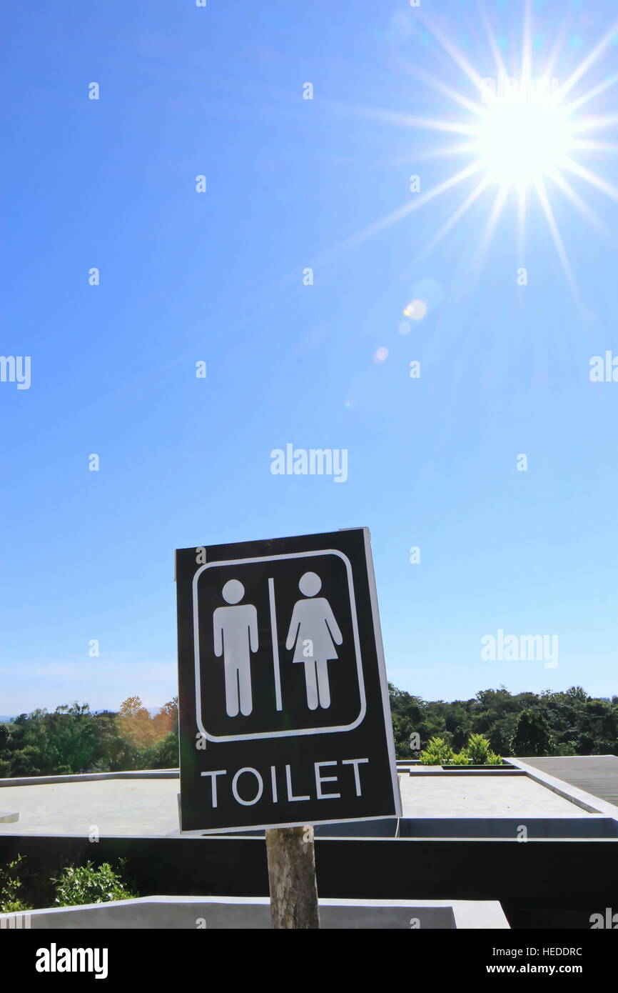 Toilettes signe avec le soleil et fond de ciel bleu Banque D'Images