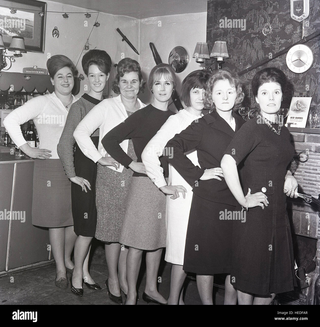Historique des années 1960, l'équipe de fléchettes pub femelle pour une photo dans le bar, avec annonces pour Watneys Red Barrel keg beer à l'écran. Banque D'Images