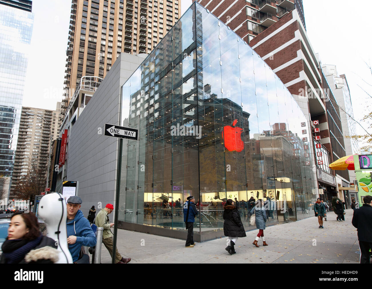 Les gens sont à pied par l'Apple Store sur Broadway et la 67e rue Ouest. Le logo dans le magasin est allumé en rouge. Banque D'Images