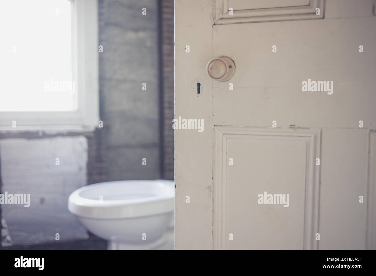 Ouvrir la porte d'une salle de bains qui est en cours de rénovation avec une nouvelle toilette Banque D'Images