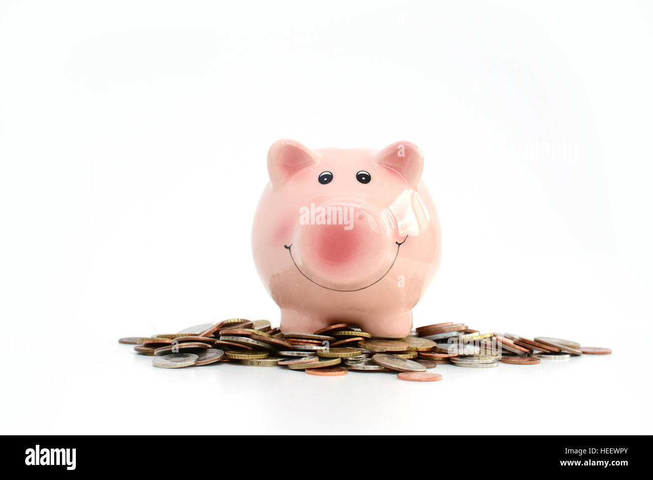 Pink piggy bank debout sur les pièces de monnaie, ce qui suggère l'argent concept d'épargne Banque D'Images