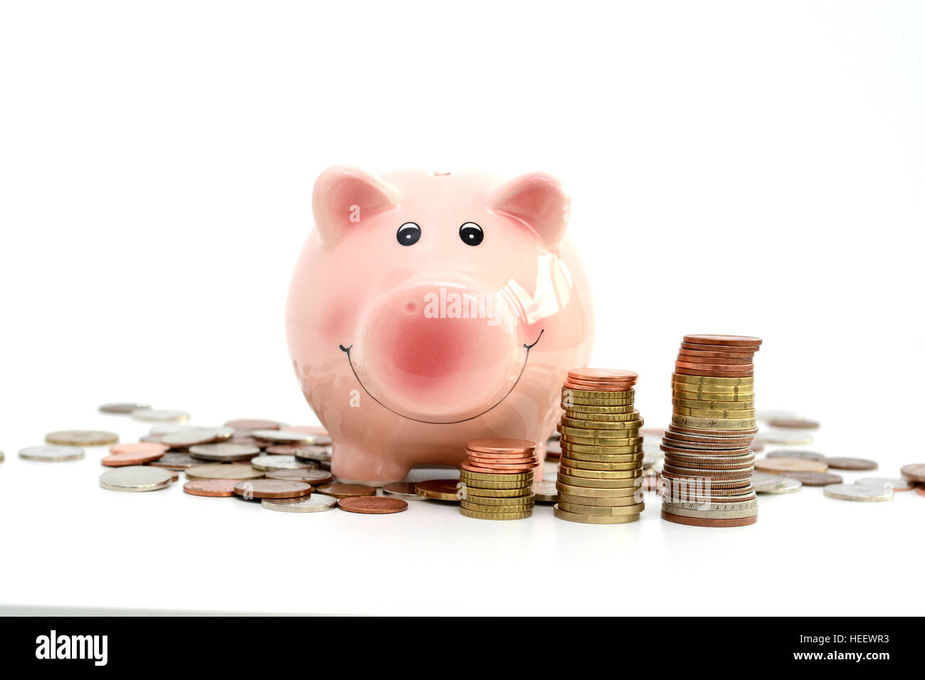 Pink piggy bank debout sur les pièces de monnaie, ce qui suggère l'argent concept d'épargne Banque D'Images