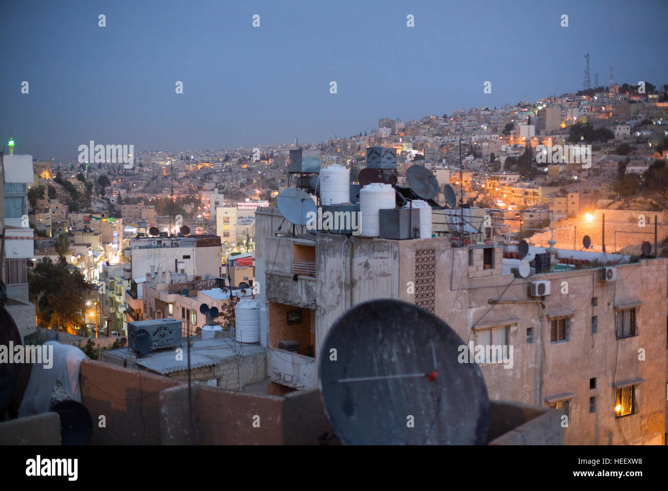Les antennes paraboliques et les réservoirs de stockage de l'eau s'asseoir sur un toit à Amman, Jordanie près de l'ancien amphithéâtre romain. Banque D'Images