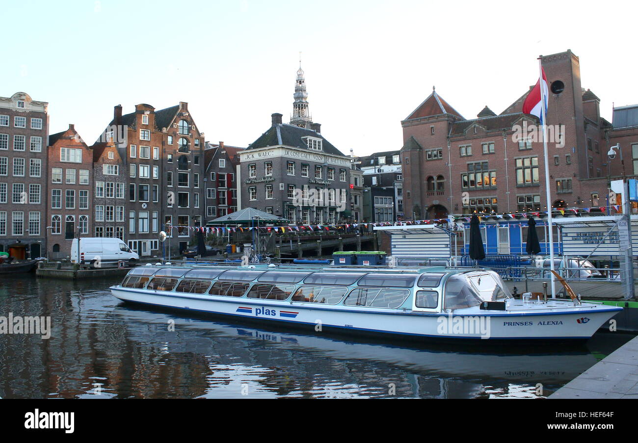 Bateau de croisière amarré au canal navigable, Damrak Amsterdam, Pays-Bas. Beurs van Berlage en arrière-plan Banque D'Images