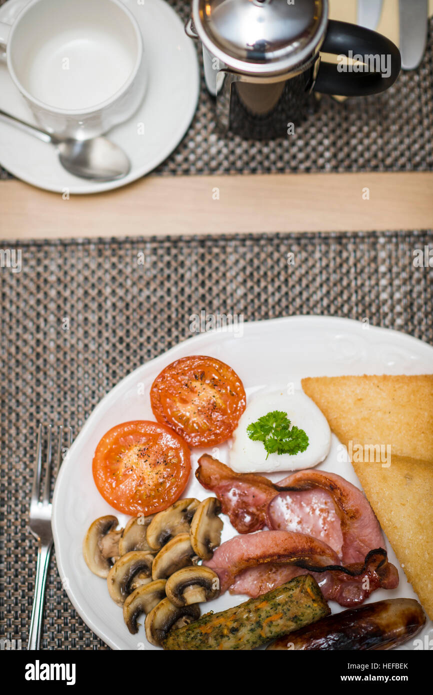 The Full Monty : Un petit-déjeuner anglais complet au plat sur une plaque blanche dans un hôtel UK (bacon, oeufs, saucisses, tomates, champignons, pain frit,) Banque D'Images